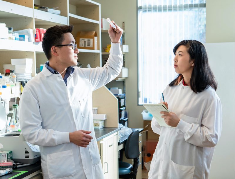 Photo of two researchers in an LJI laboratory. Chan Wang “Jerry” Lio, Ph.D. (left), and Allison Bien