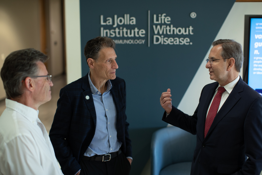 Three men stand and talk in the LJI Atrium