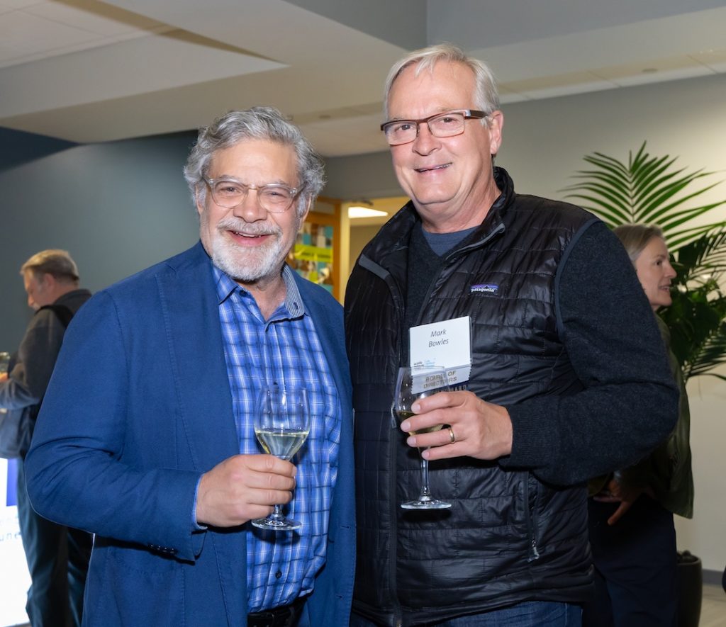 Tom Tullie and Mark Bowles at a reception. They are holding drinks and smiling