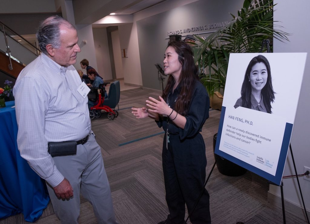 Photo of a seminar attendee (left) speaking with an LJI scientist in the LJI Atrium