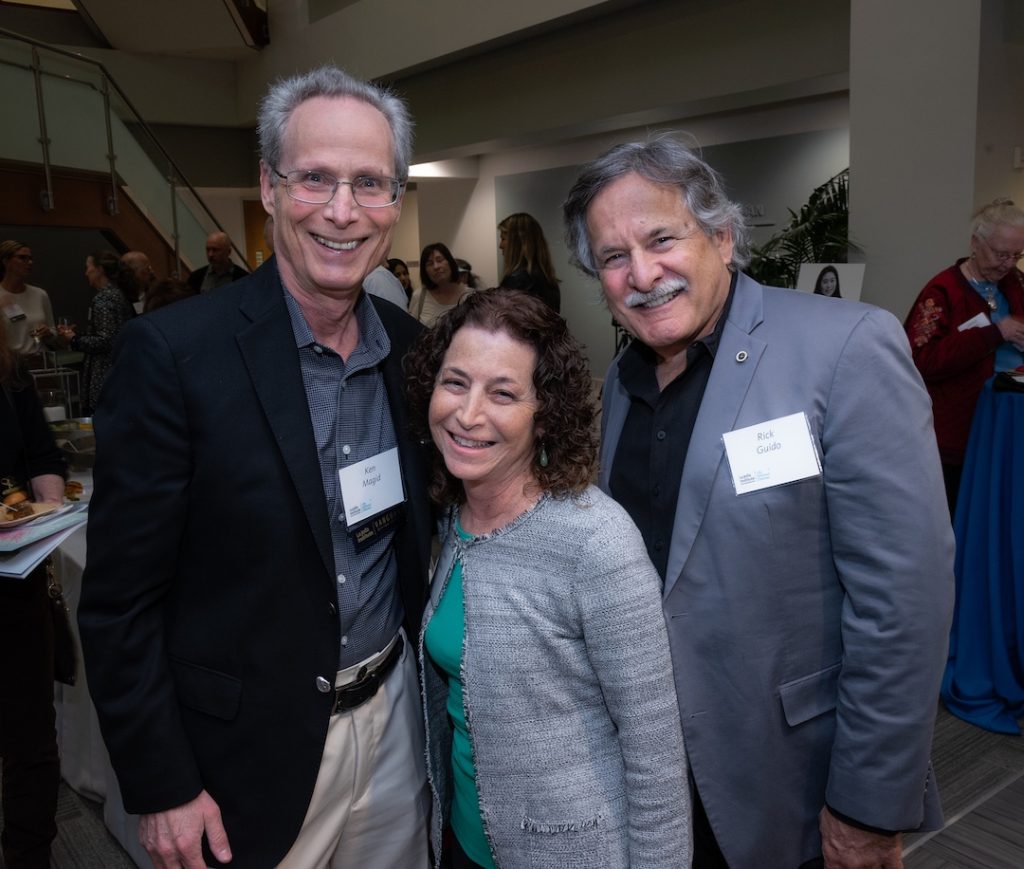 Posed photo of three people smiling at the camera in the LJI Atrium