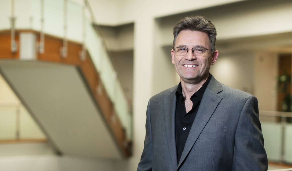 Portrait photo of Dr. Croft. He stands in the Institute and smiles at the camera.